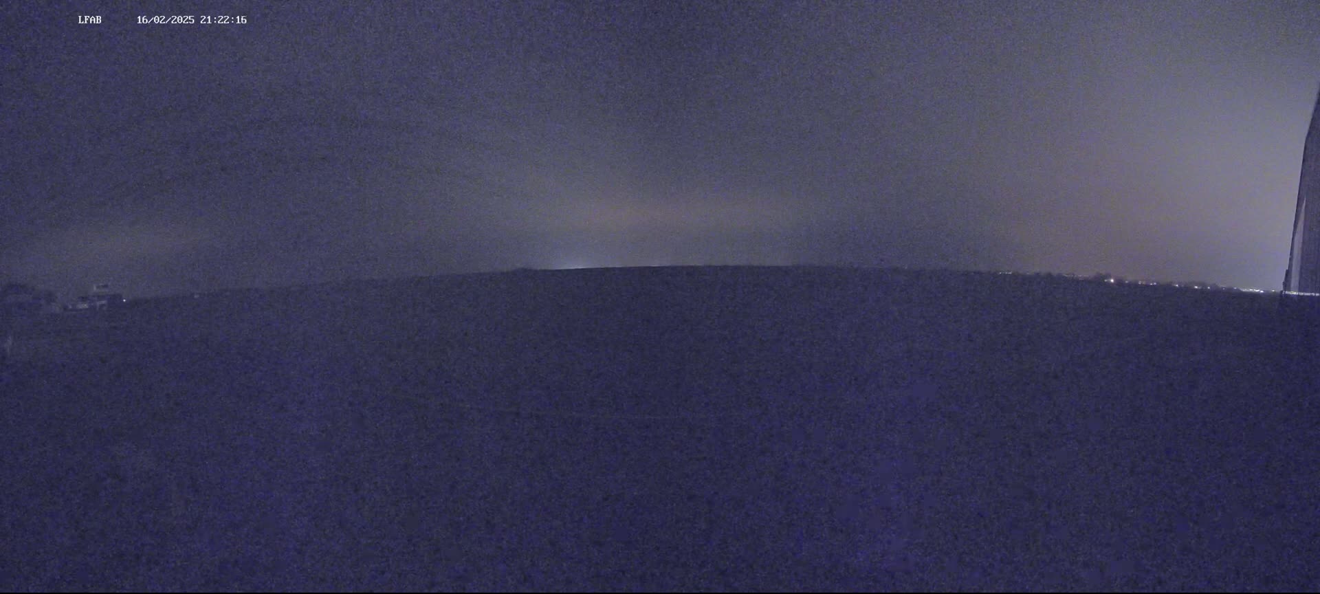 A dark, nighttime landscape is visible under an overcast sky.