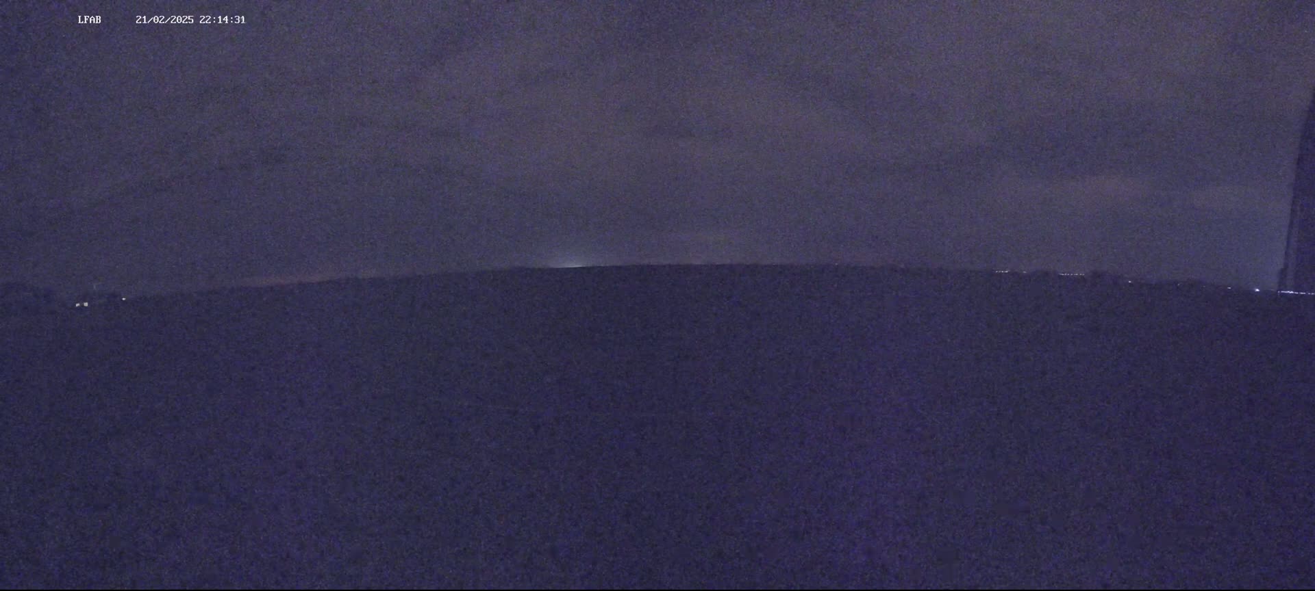 A dark, nighttime landscape is visible under a cloudy sky.