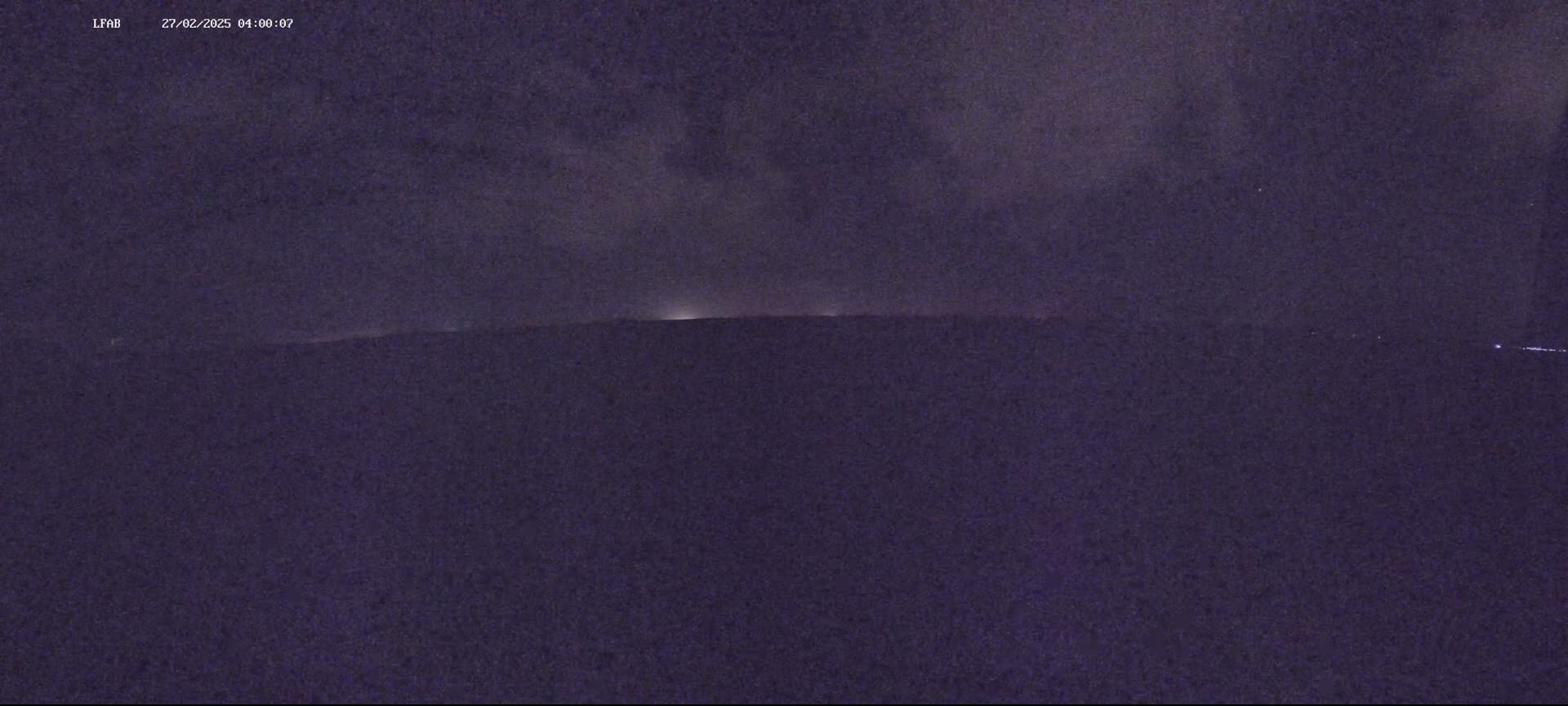 A dark, nighttime landscape is visible under a cloudy sky.
