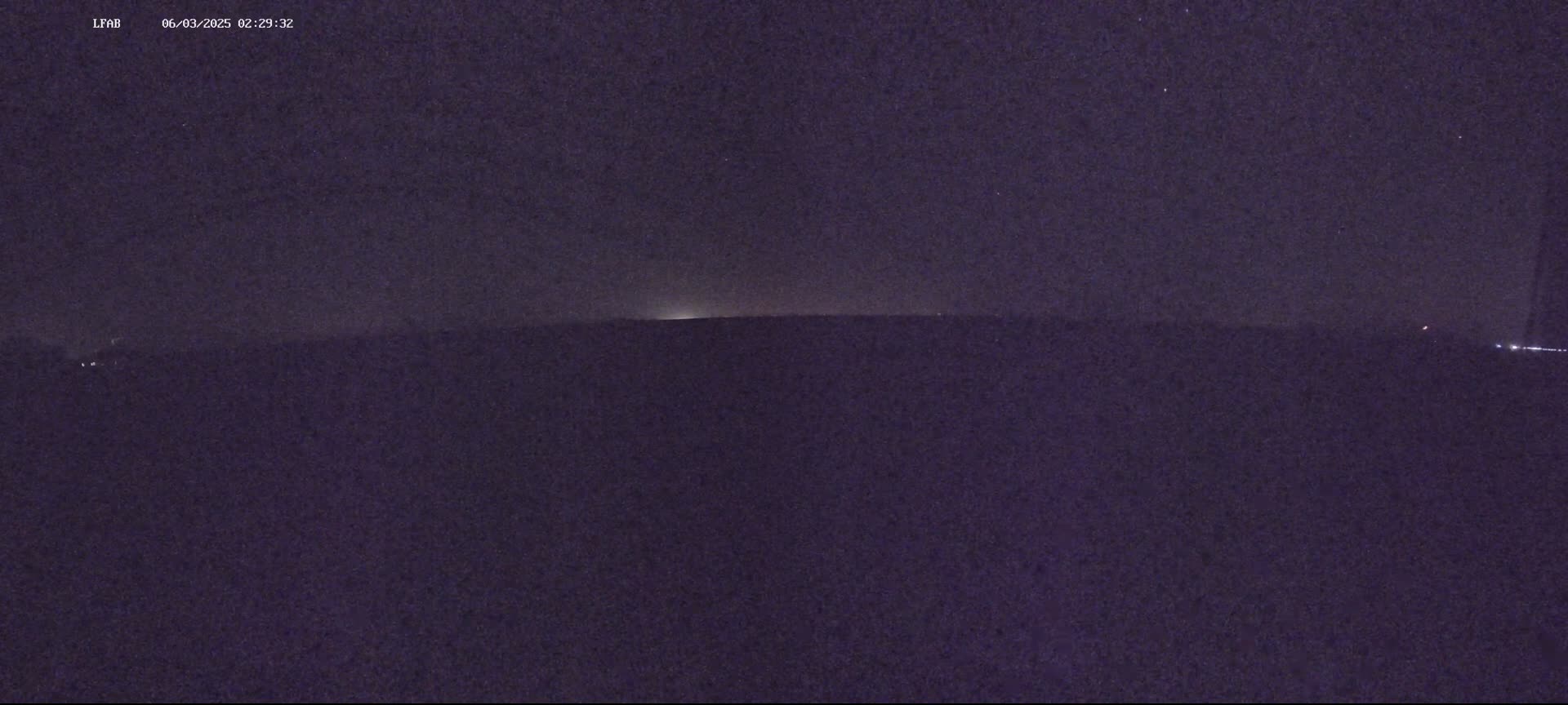 A dark, nighttime landscape is visible under a clear, starry sky.