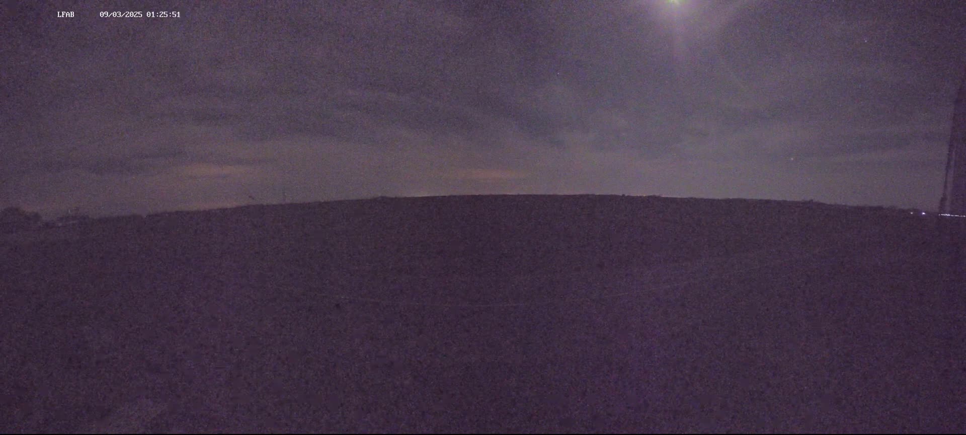 A dark, flat landscape is visible under a night sky with a few clouds and a bright moon or light source.
