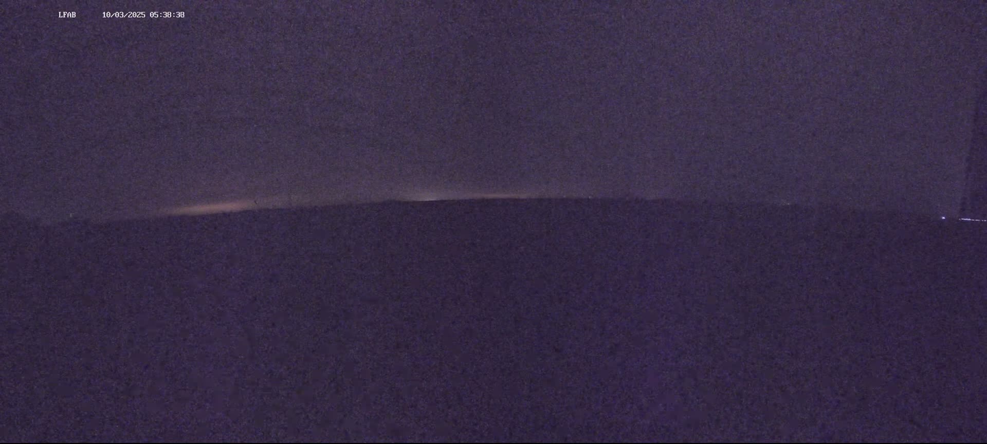 A dark, flat landscape is visible under a dusky, possibly pre-dawn sky.