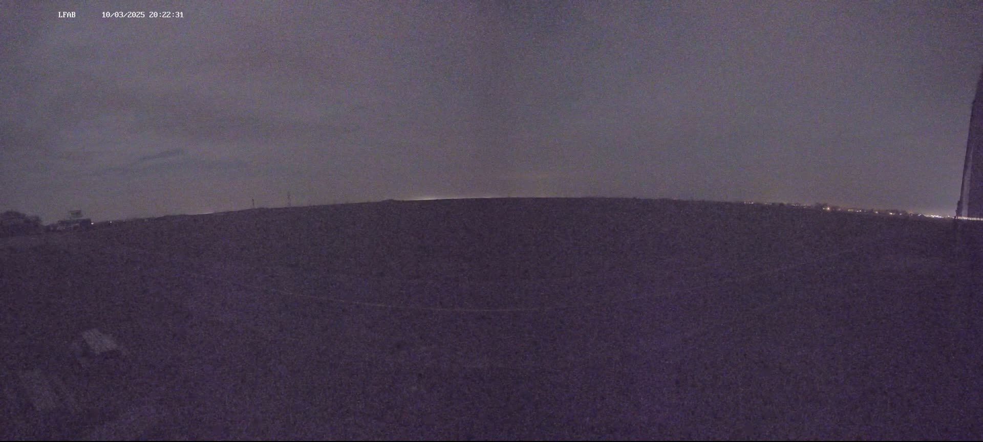 A dark, flat landscape is visible under a dusky night sky.