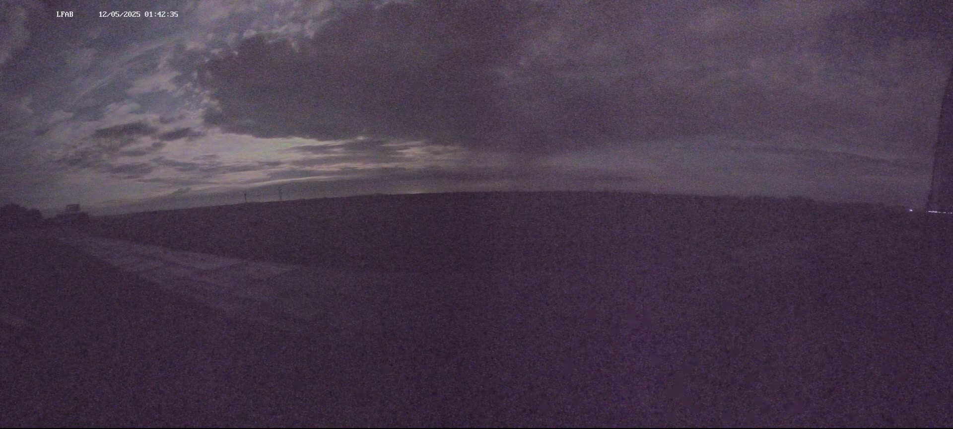 A dark, overcast sky hangs over a flat, dark landscape at night.