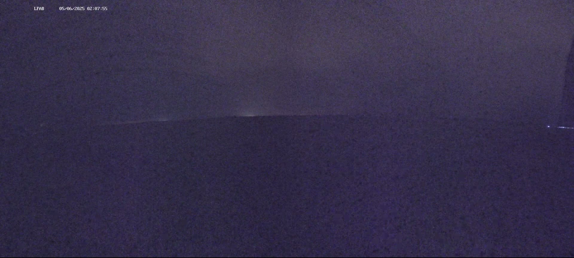 A dark, nighttime landscape is visible under a cloudy sky.