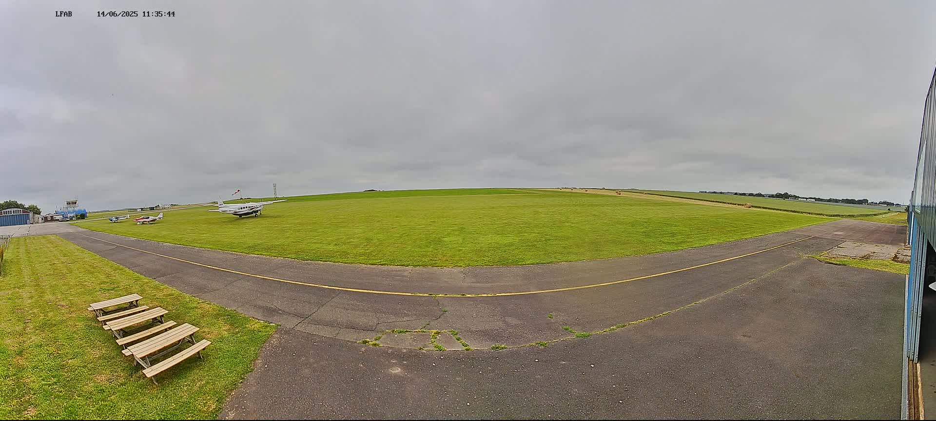 Several small airplanes are parked on a grassy airfield under an overcast sky.