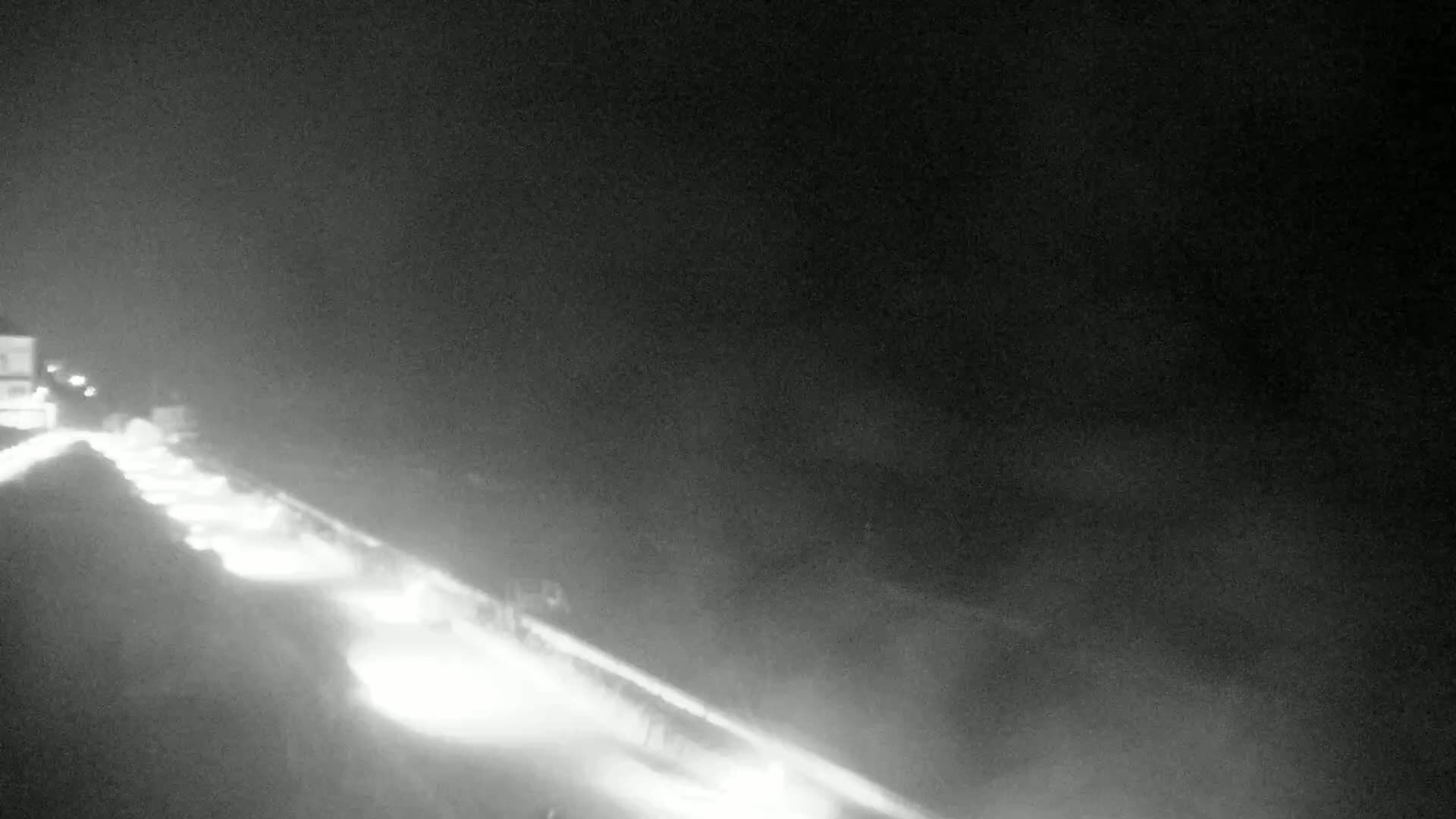 A nighttime, low-light view of a highway with several vehicles traveling in the same direction.