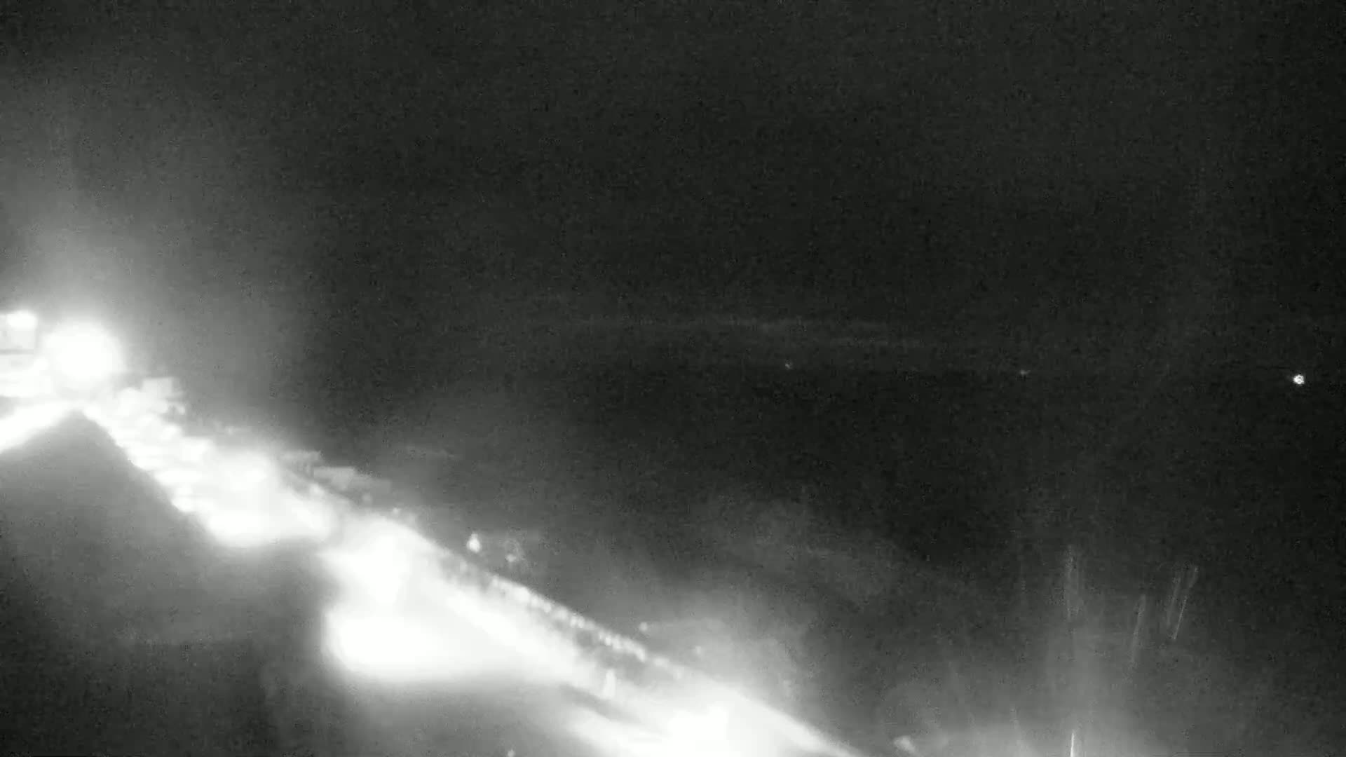 A nighttime, low-visibility view shows a highway with bright headlights from oncoming traffic.