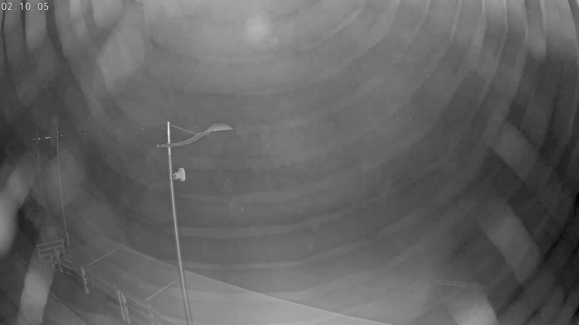 A nighttime, low-light image shows a portion of a roadway, possibly inside a tunnel, with a single lamppost visible.