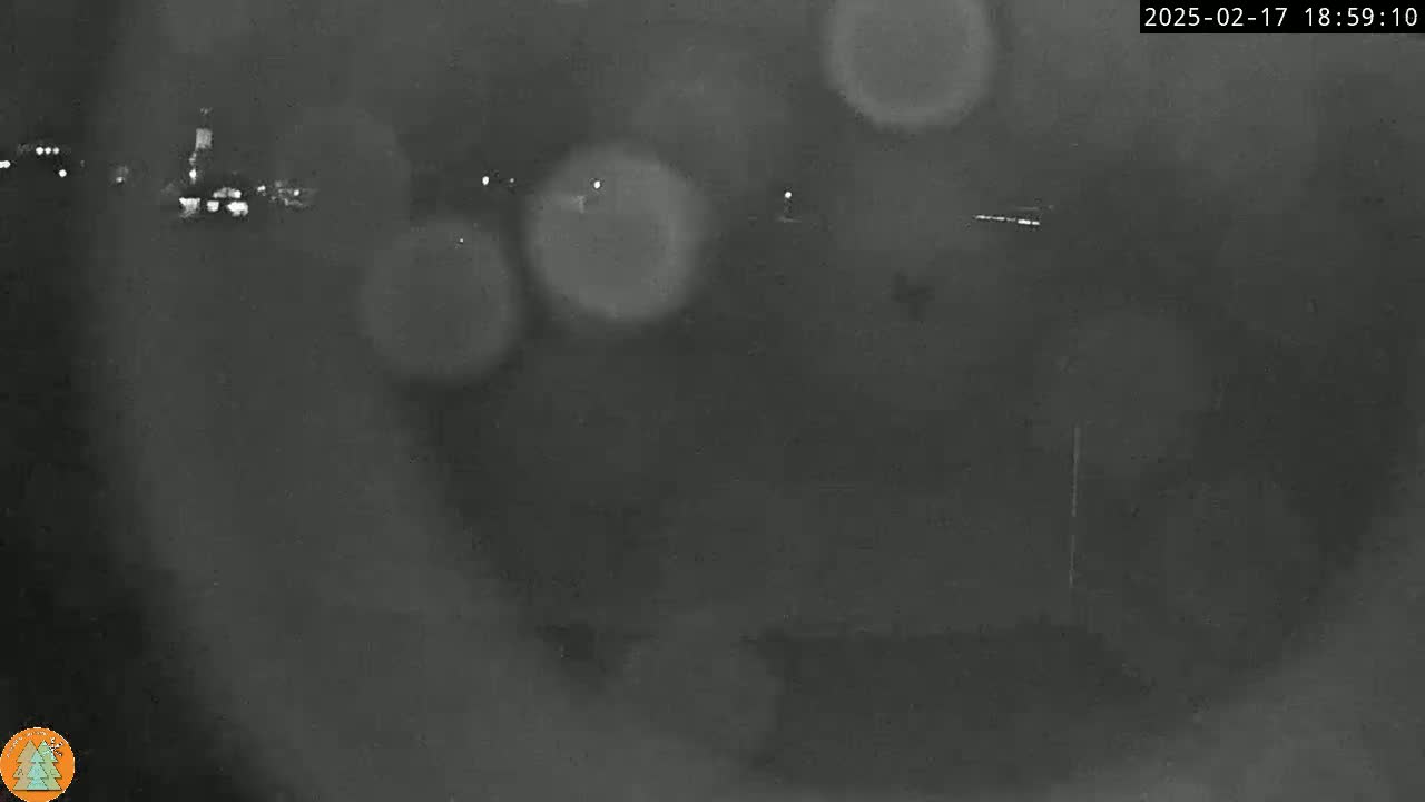 A blurry, nighttime image shows indistinct lights in the distance and what appears to be light rain or snow.