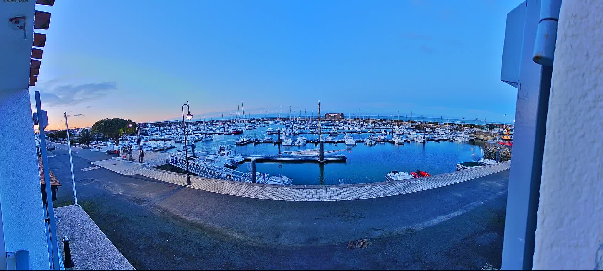A calm harbor filled with numerous boats is seen at dusk under a clear sky.