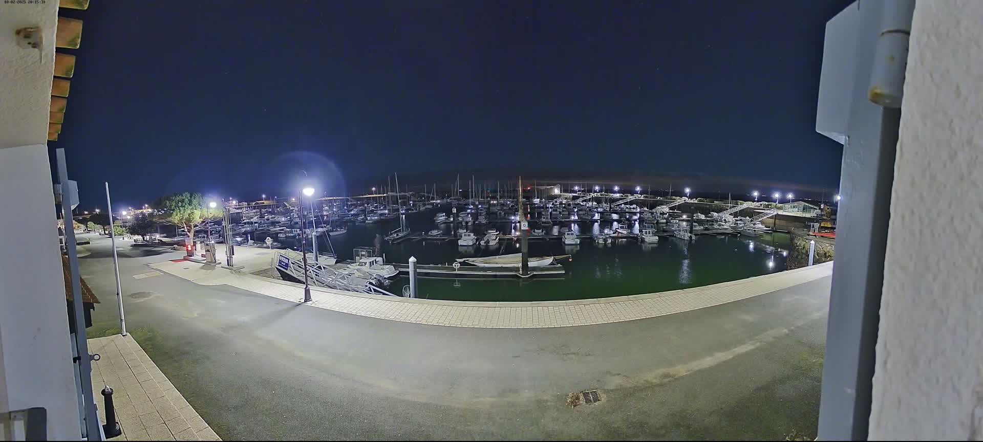 A nighttime view of a marina filled with numerous boats under a clear, dark sky.