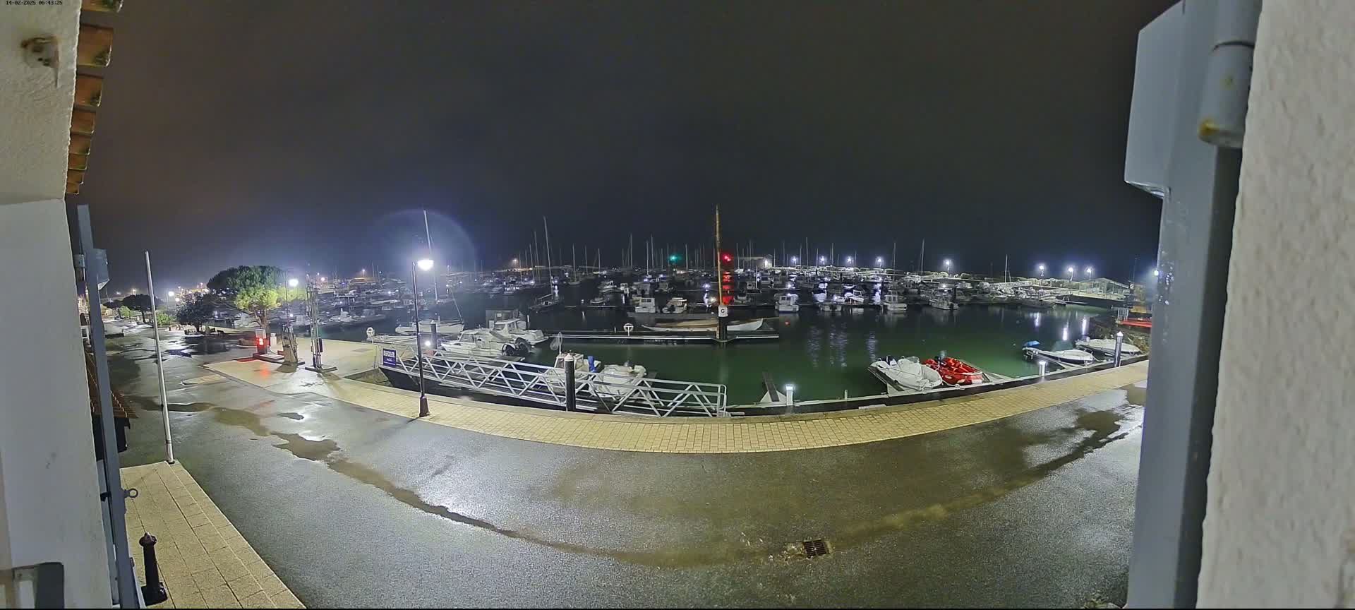 A wet, nighttime view of a marina filled with boats under a dark, overcast sky.