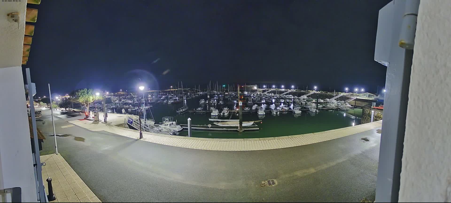 A nighttime view of a marina filled with boats, illuminated by artificial lights.