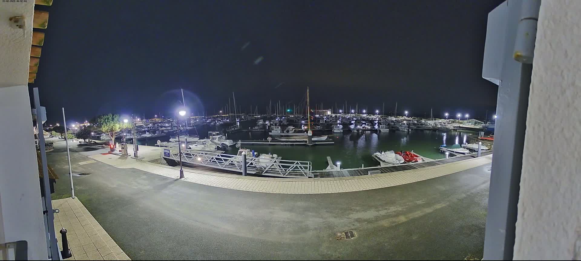 A nighttime view of a marina filled with numerous boats and yachts, under a dark sky.