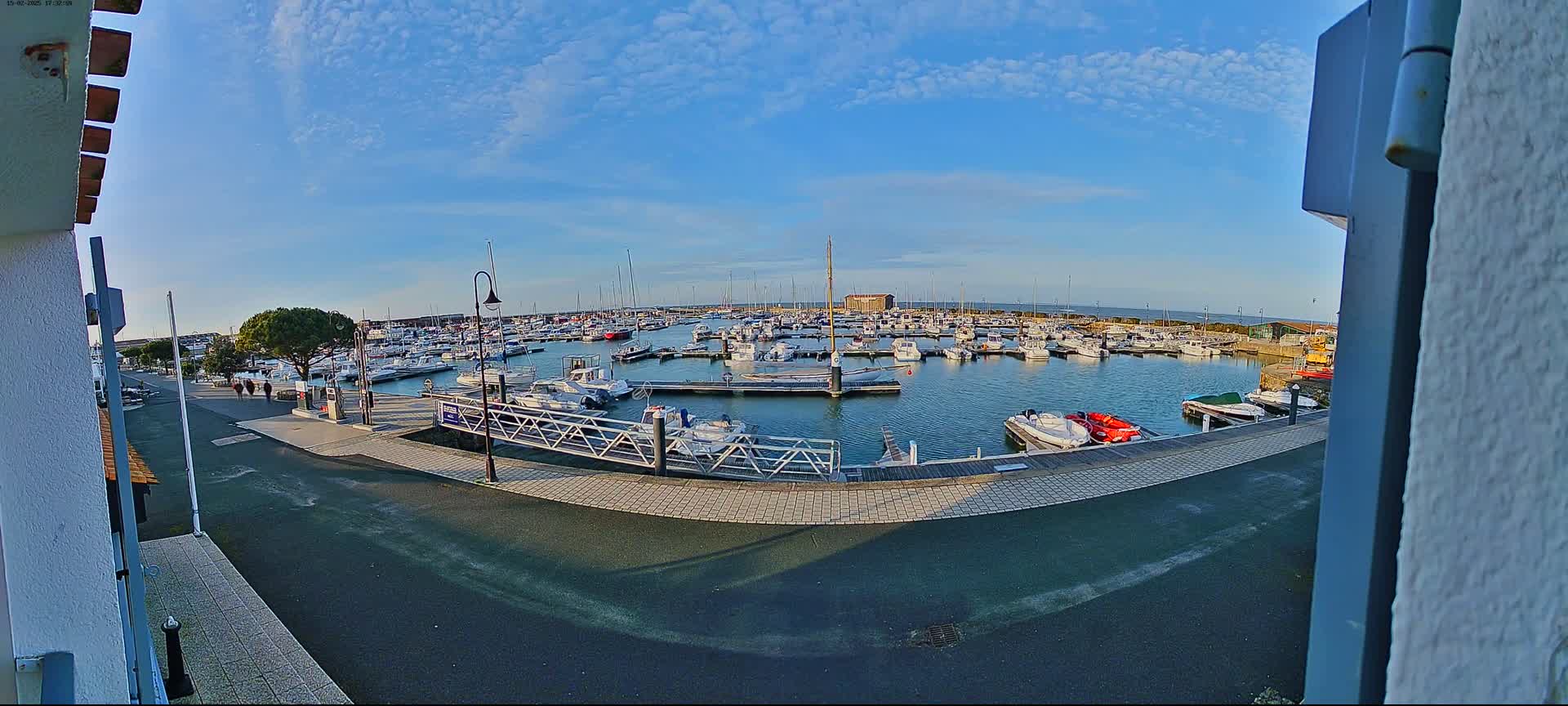 A marina filled with numerous boats under a mostly clear, sunny sky.