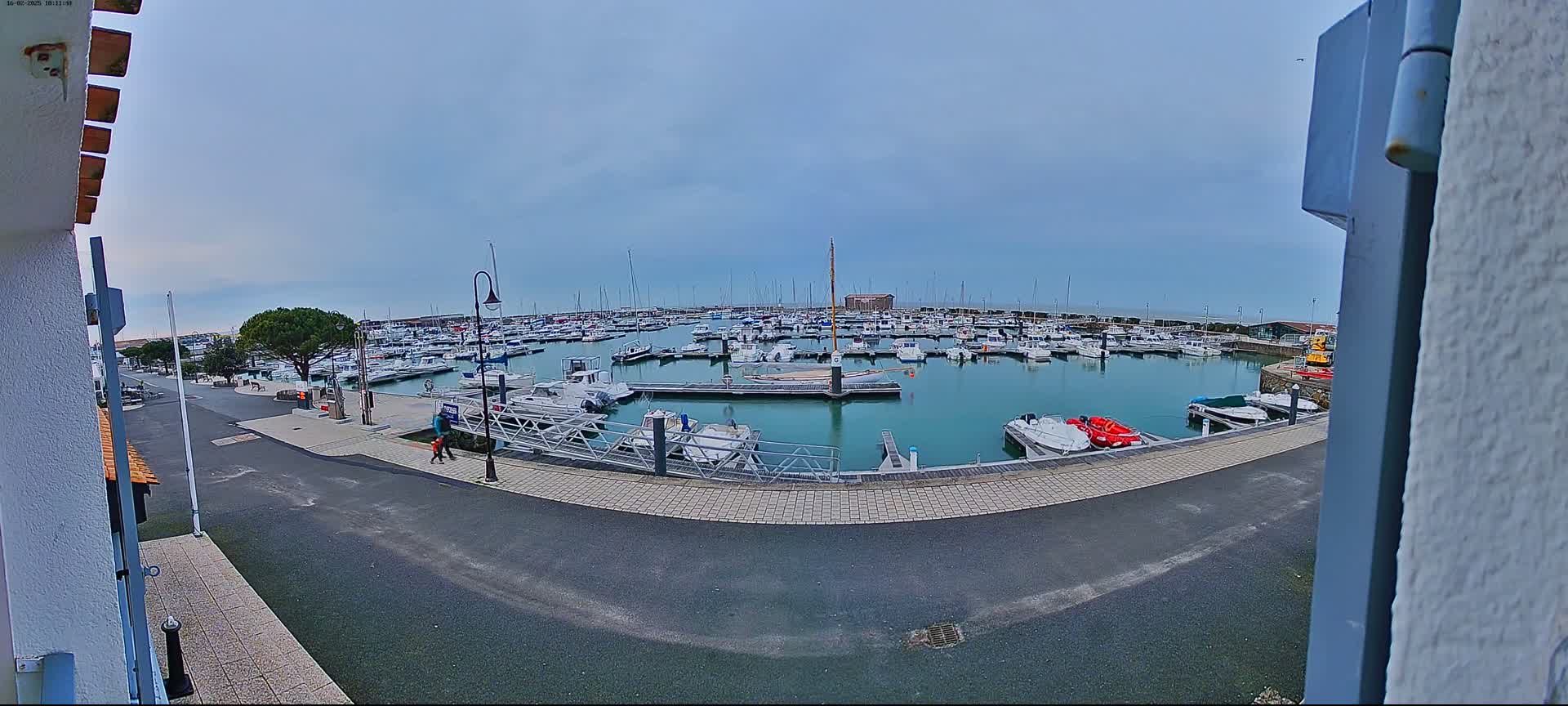 A marina filled with numerous boats is seen on a mostly cloudy day.