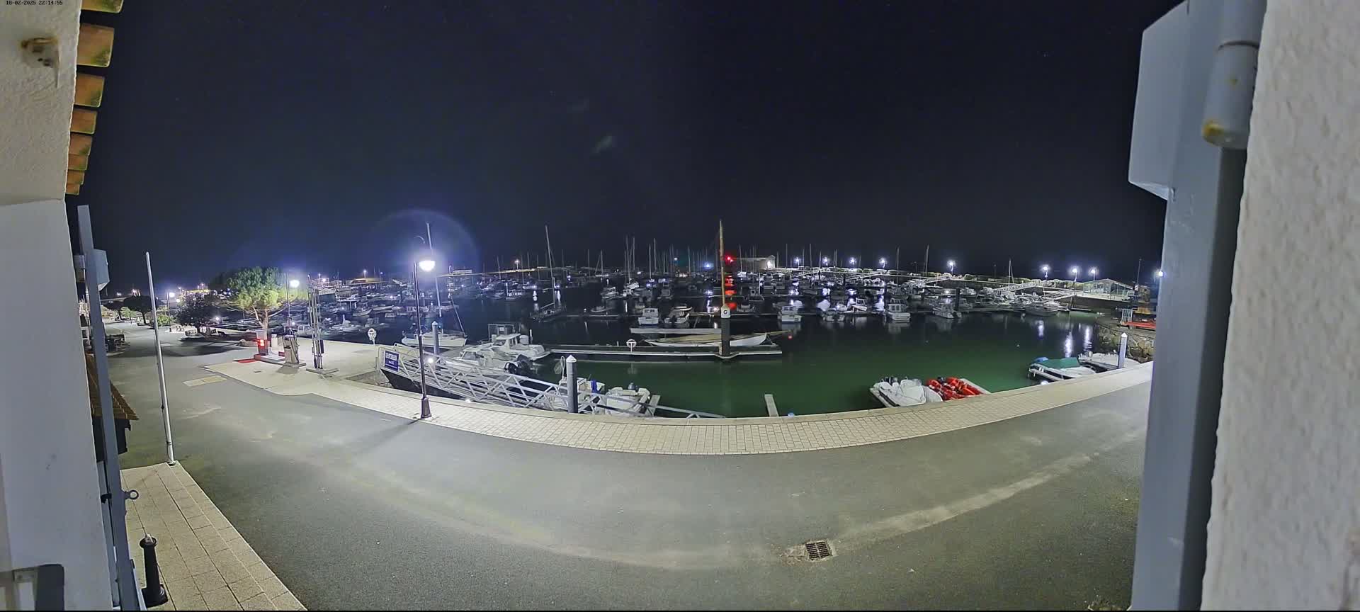 A nighttime view of a marina filled with boats under a clear, dark sky.