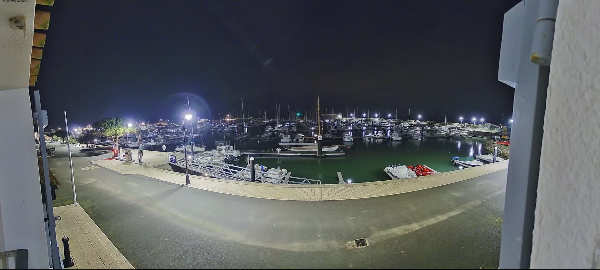A nighttime view of a marina filled with numerous boats, illuminated by artificial lights.