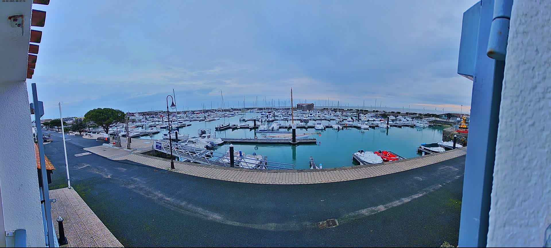 A marina filled with numerous boats is seen under an overcast sky.