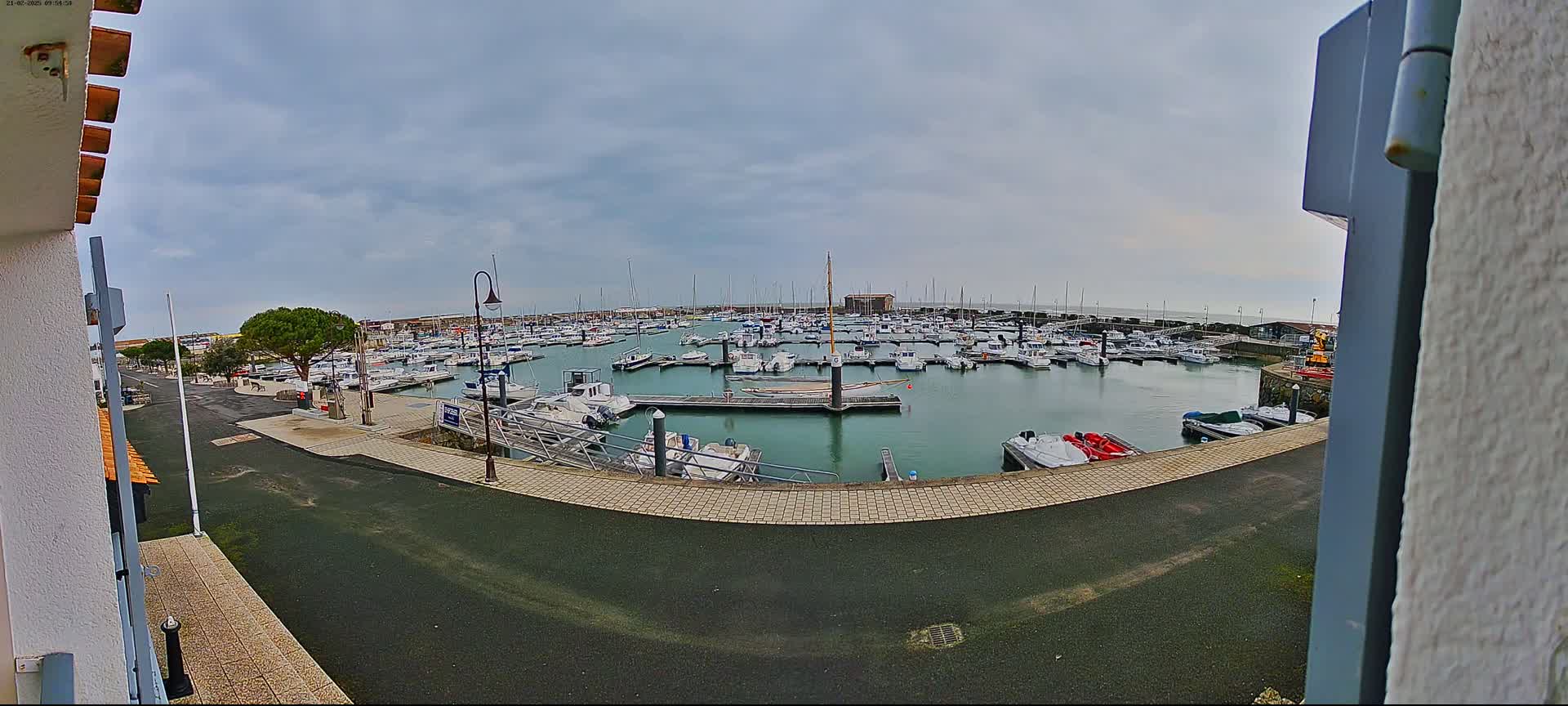 A marina filled with numerous boats is seen under an overcast sky.