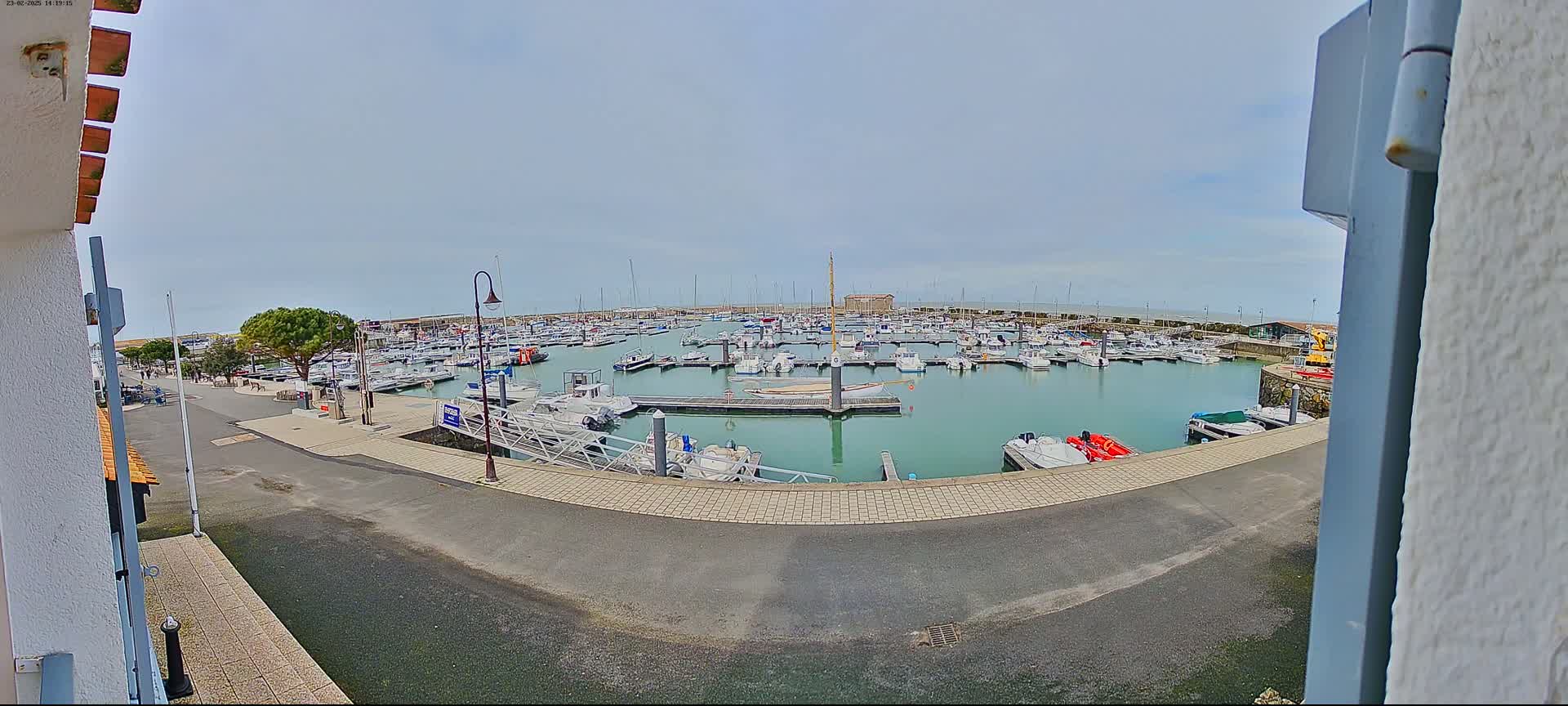 A marina filled with numerous boats is seen on a partly cloudy day.