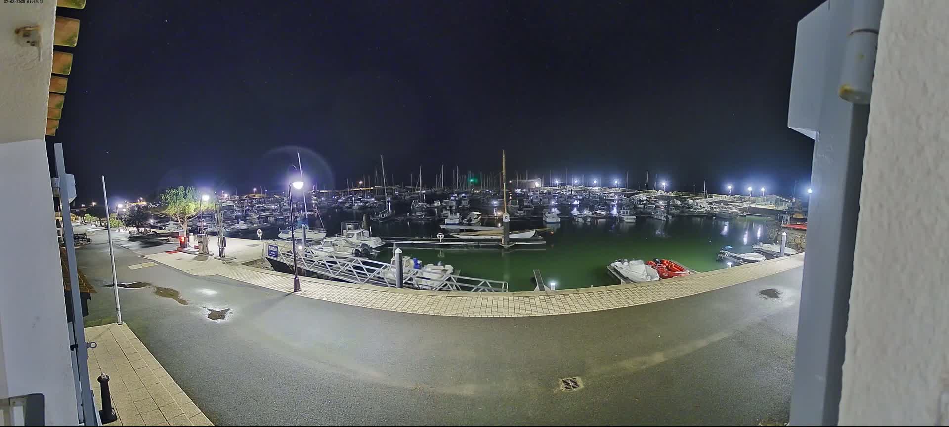 A marina filled with numerous boats is shown at night under a clear, starry sky.