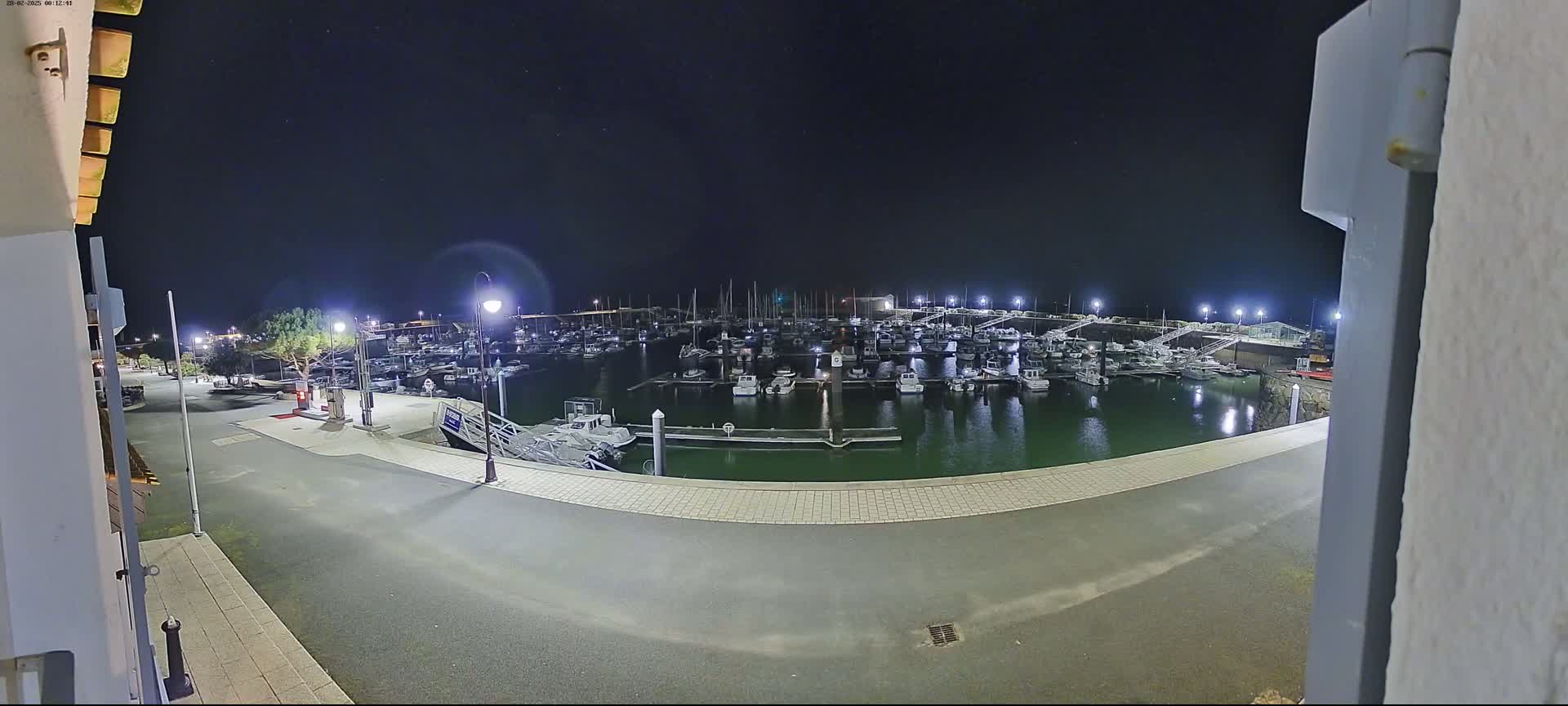 A nighttime view of a marina filled with docked boats under a clear, starry sky.