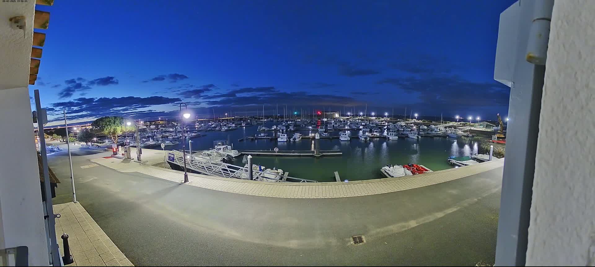 A marina filled with boats at dusk under a mostly clear blue sky.