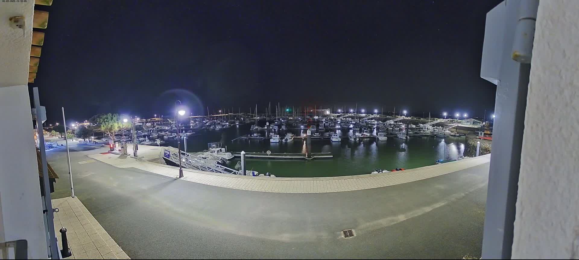 A nighttime view of a marina filled with boats under a clear, dark sky.