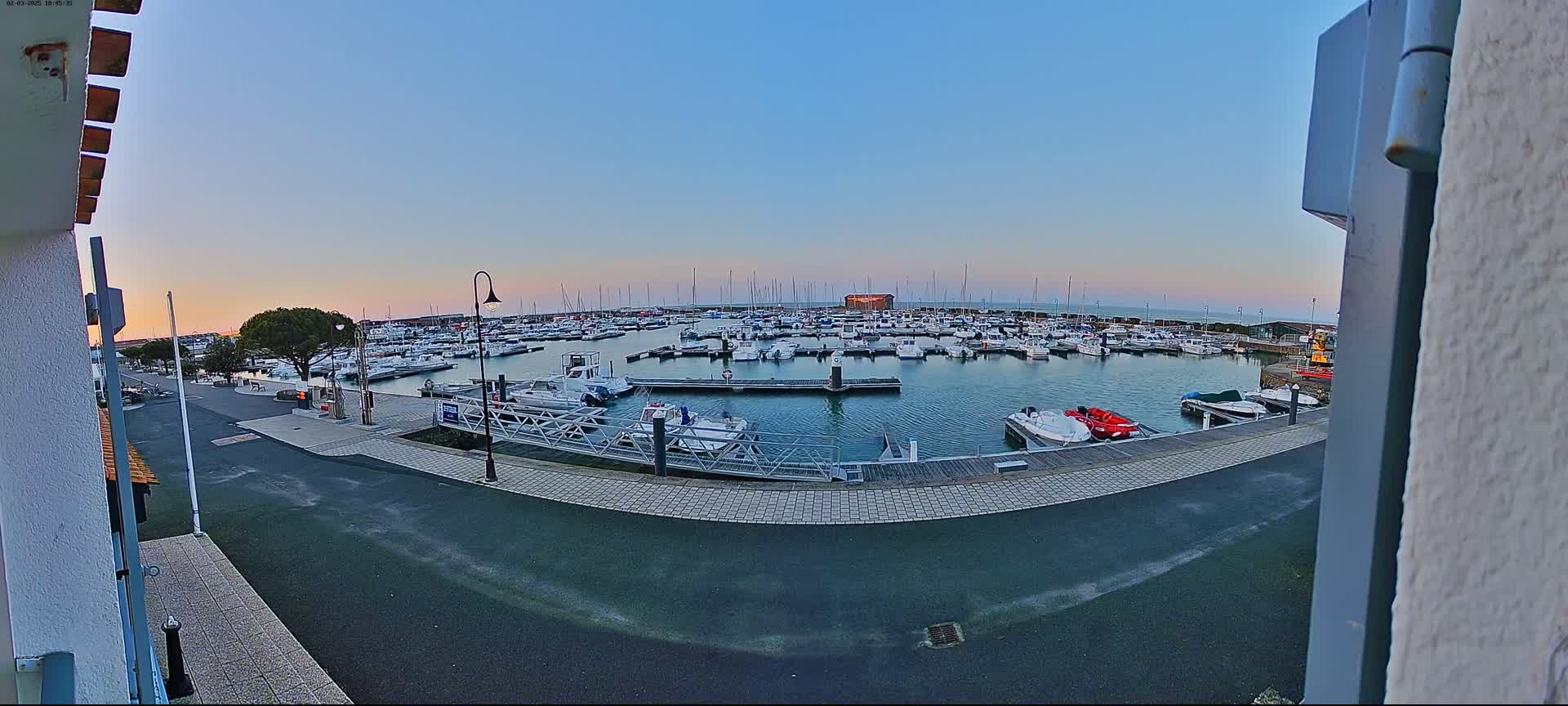 A marina filled with numerous boats is seen at sunset under a clear sky.