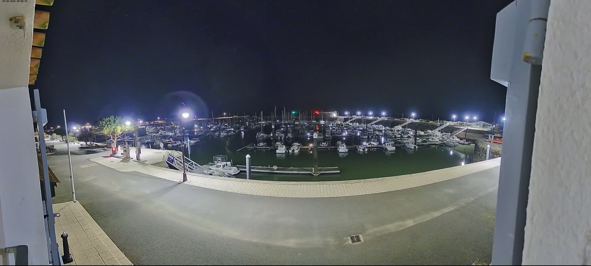 A nighttime view of a marina filled with boats under a clear, starry sky.