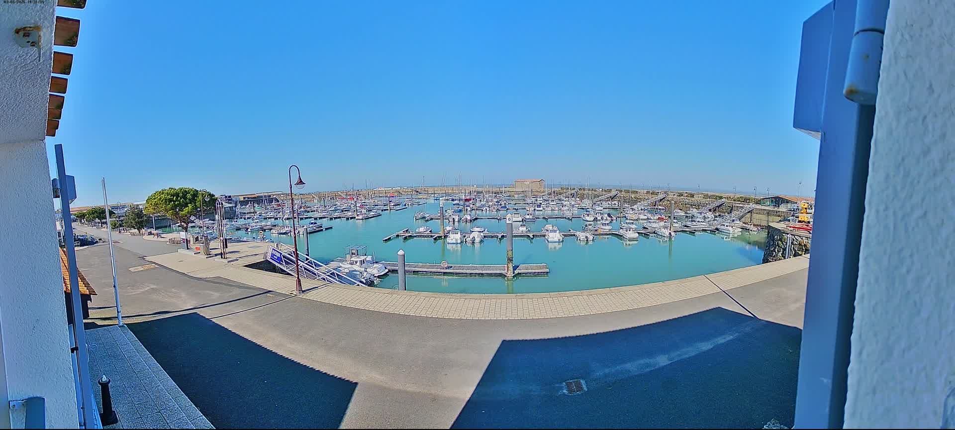 A marina filled with numerous boats is seen on a sunny day.