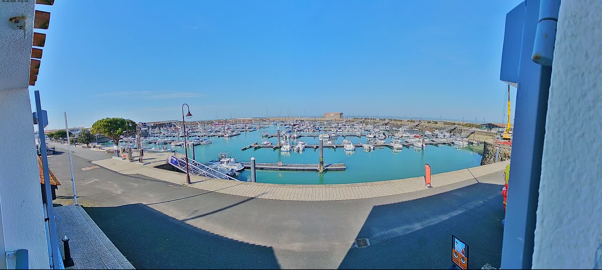 A marina filled with numerous boats is seen on a sunny day.
