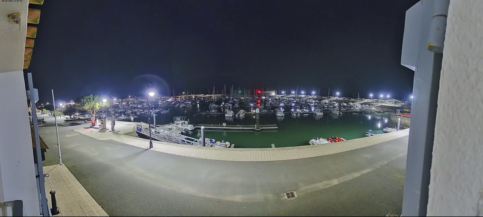 A marina filled with boats is illuminated at night under a clear, starry sky.