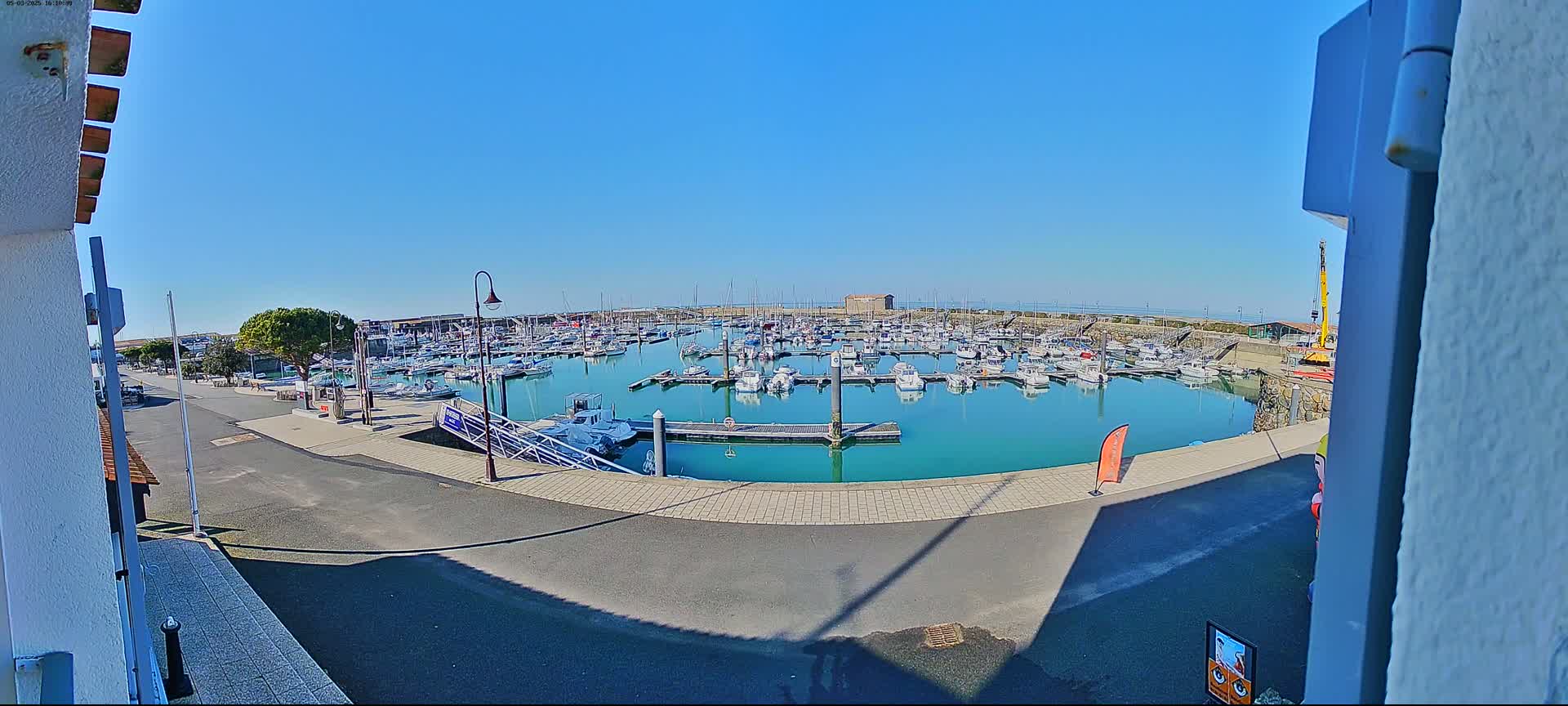 A marina filled with numerous boats is seen on a sunny day.