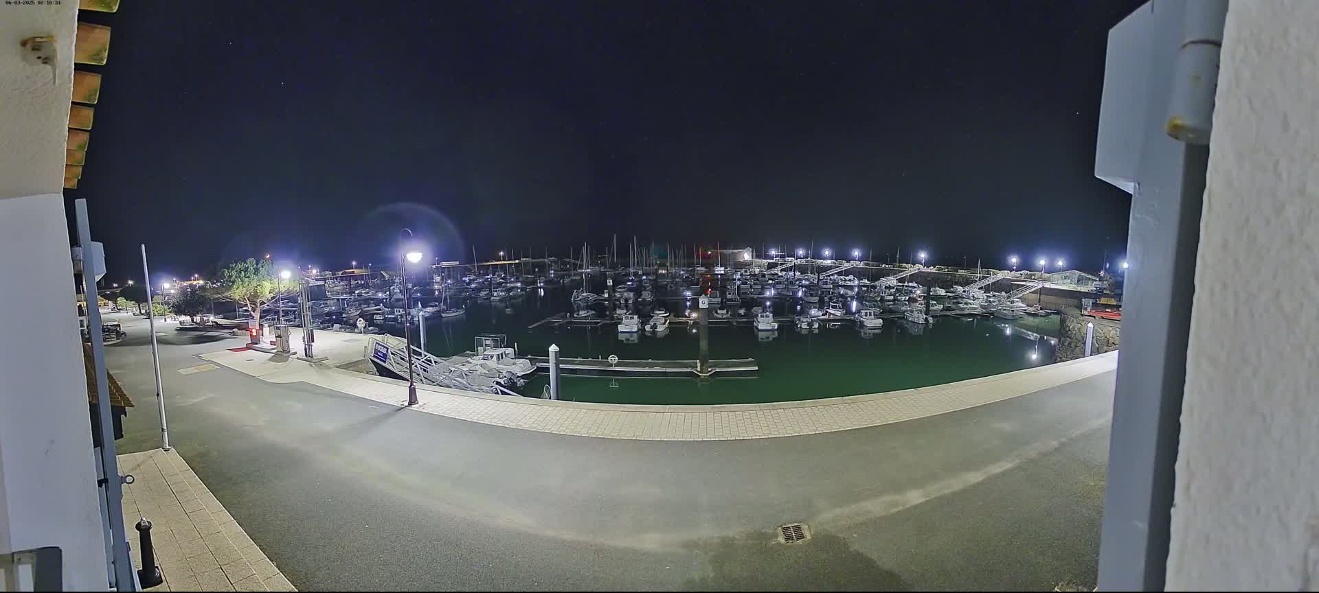 A nighttime view of a marina filled with numerous boats under a clear, dark sky.