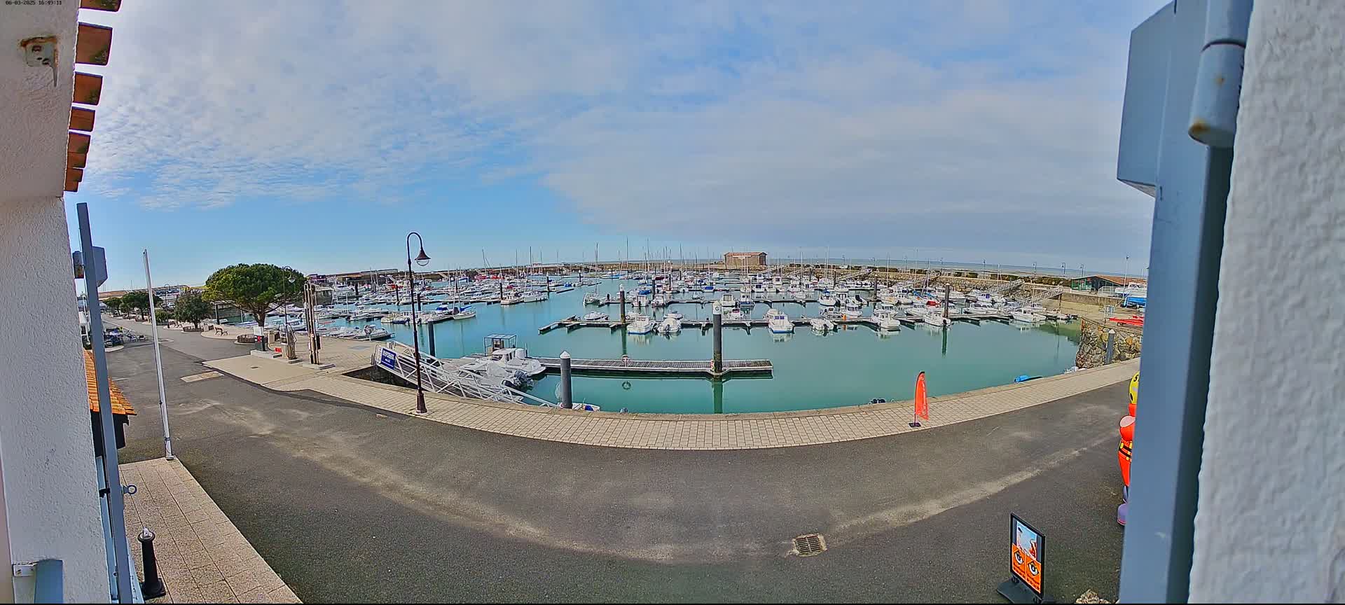 A marina filled with numerous boats is seen on a partly cloudy day.