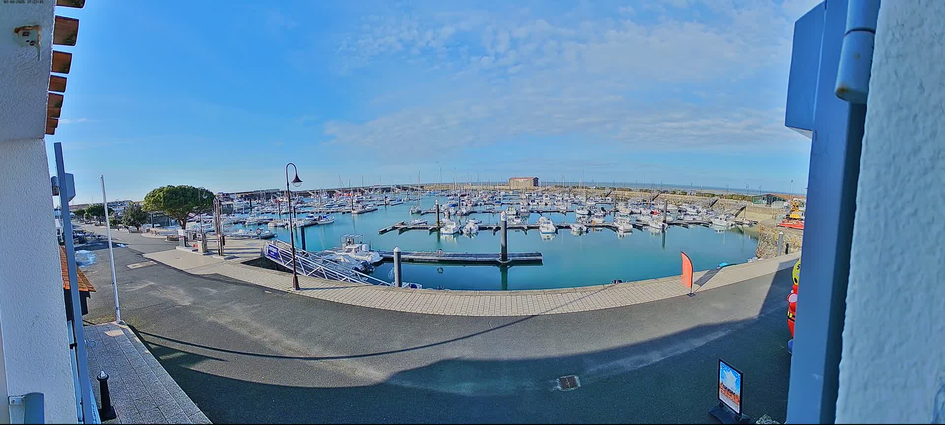 A marina filled with numerous boats on a sunny day with a clear blue sky.