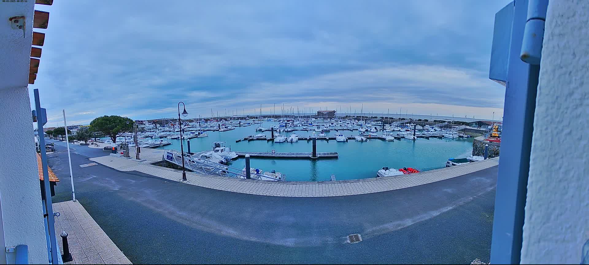 A marina filled with numerous boats is seen under a cloudy sky.