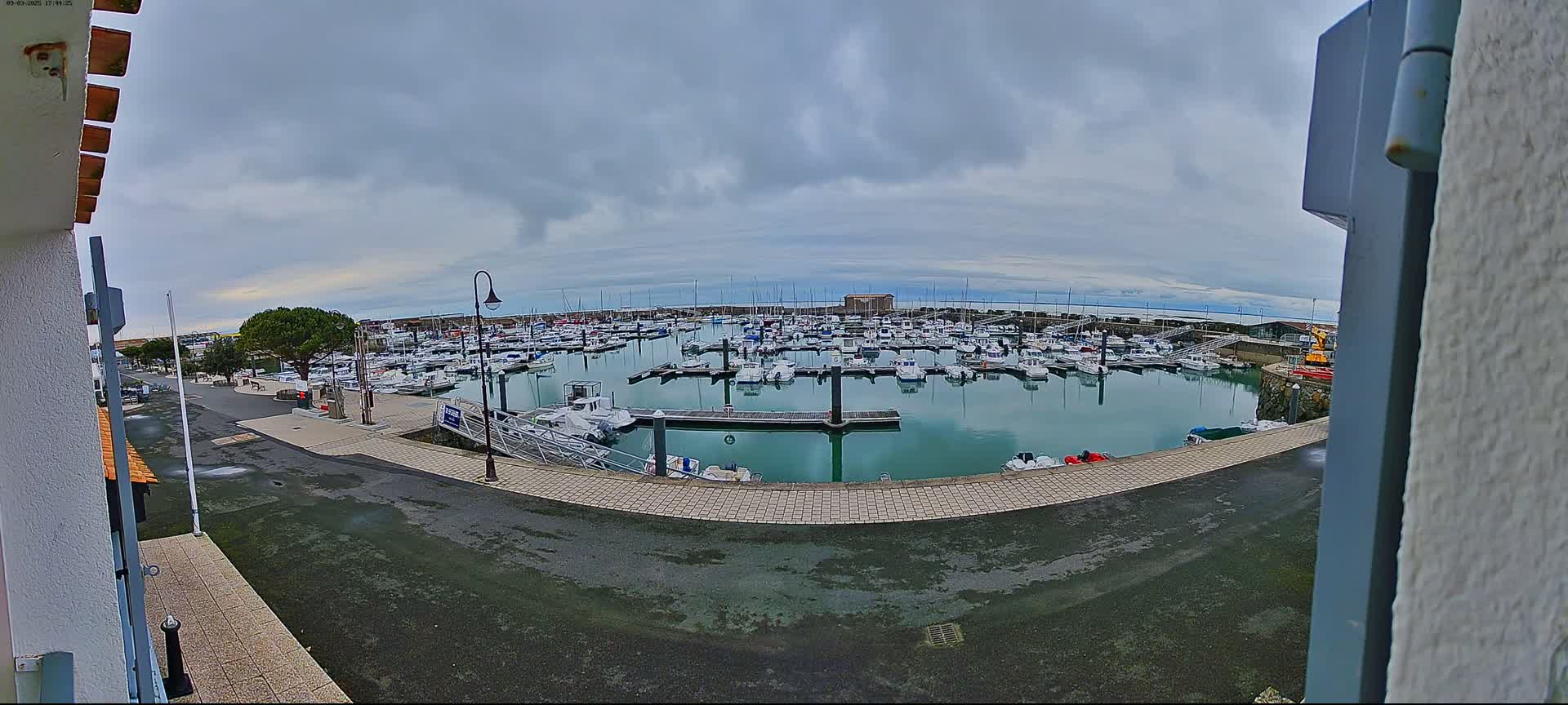 A harbor filled with numerous boats is seen under a cloudy sky.
