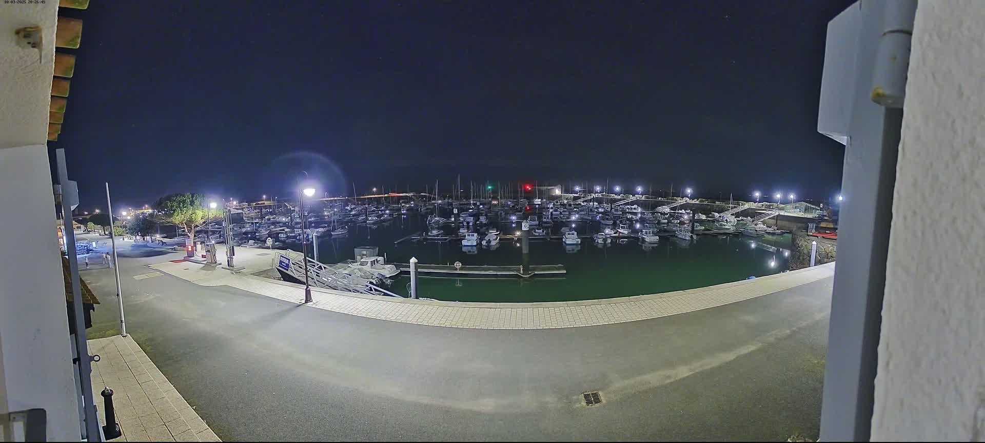 A nighttime view of a marina filled with numerous boats under a clear, dark sky.