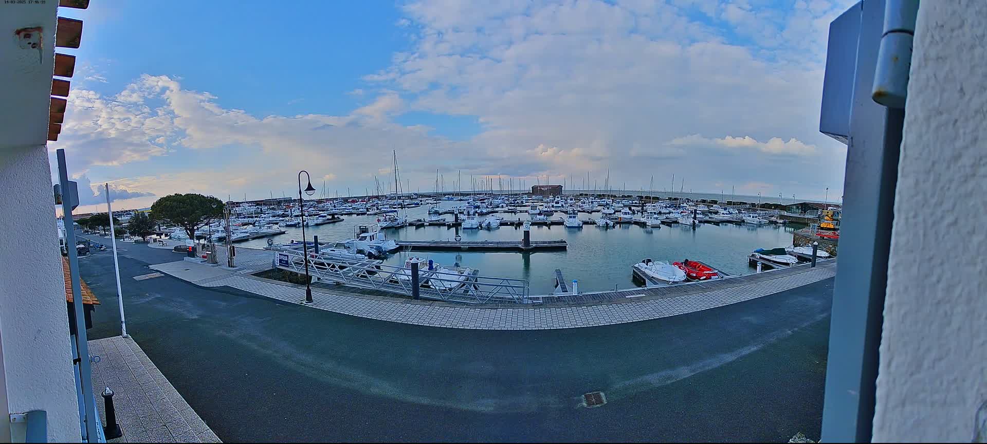 A marina filled with numerous boats under a partly cloudy sky.