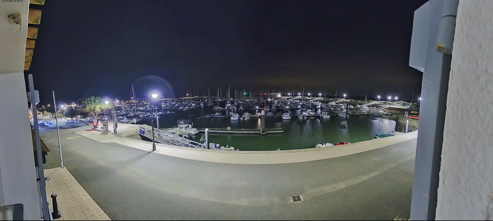 A nighttime view of a marina filled with numerous boats under a clear, dark sky.