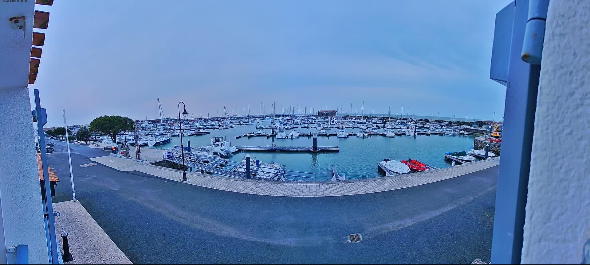A marina filled with numerous boats is visible under an overcast sky.