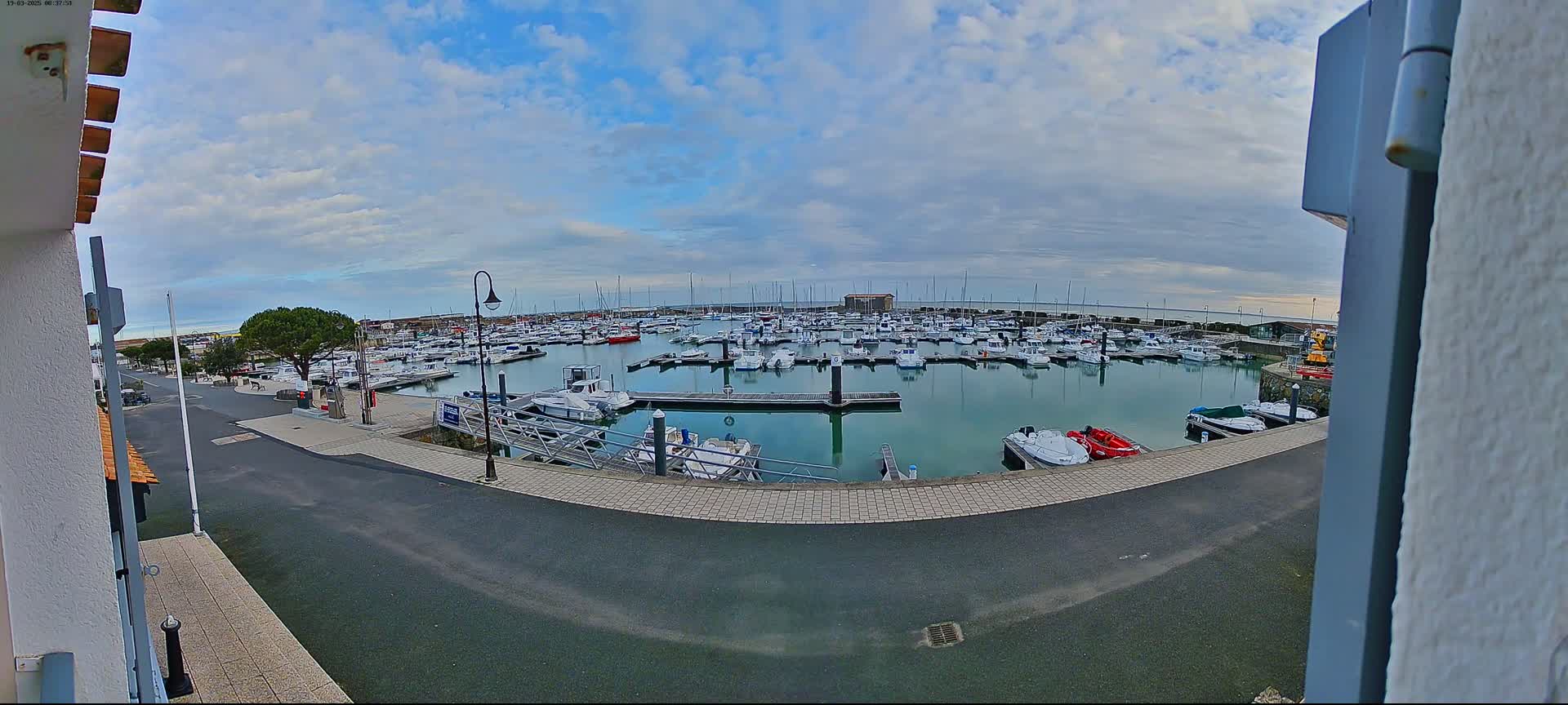 A marina filled with numerous boats under a partly cloudy sky.