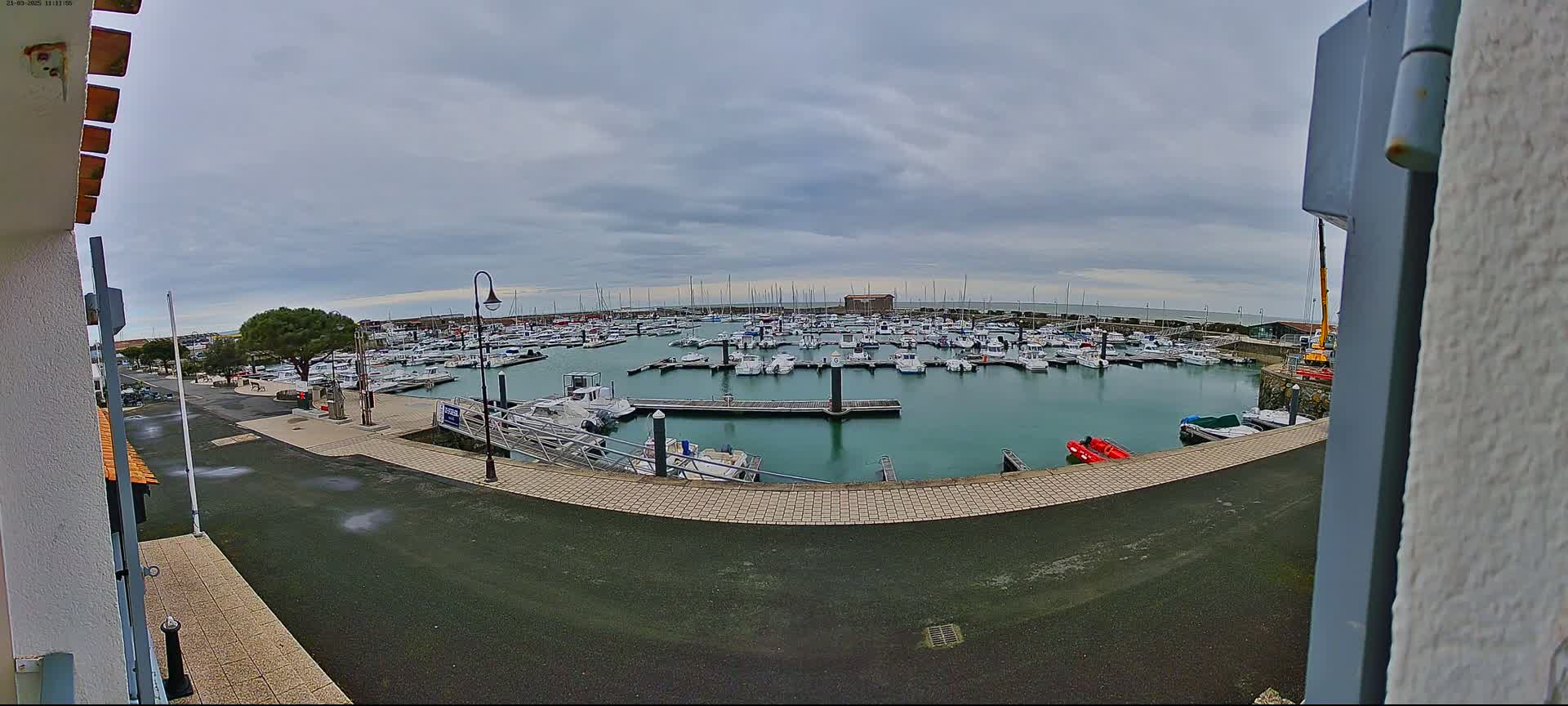 A marina filled with numerous boats is seen under an overcast sky.