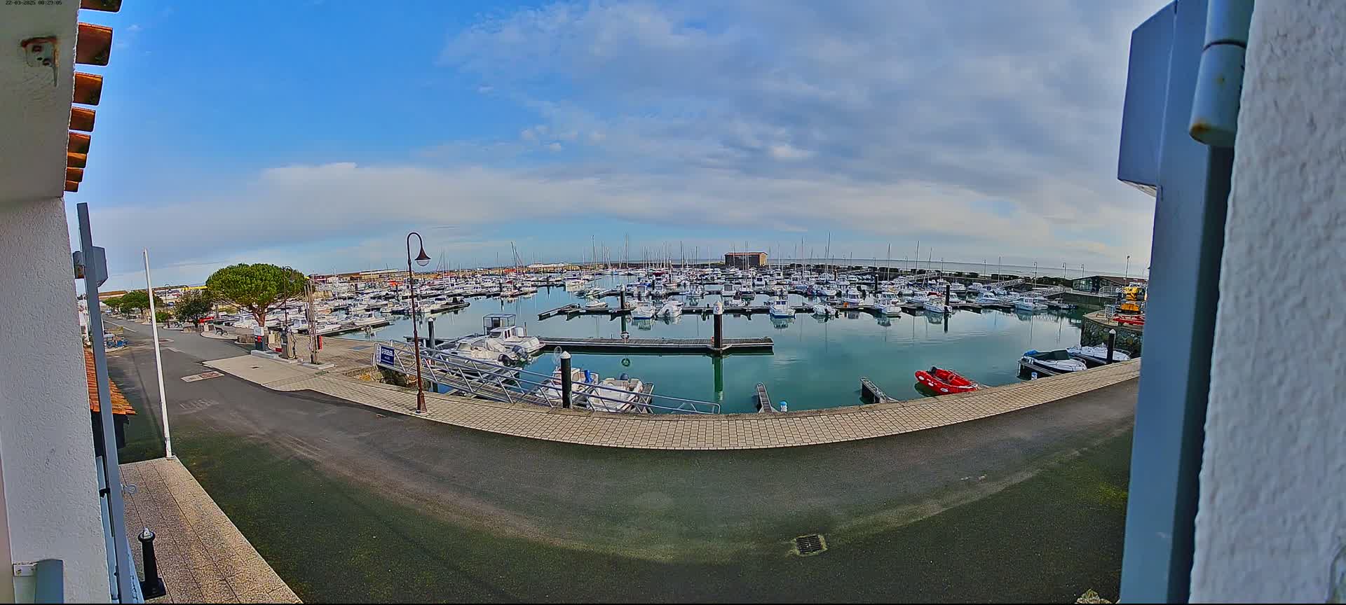A marina filled with numerous boats under a partly cloudy sky.
