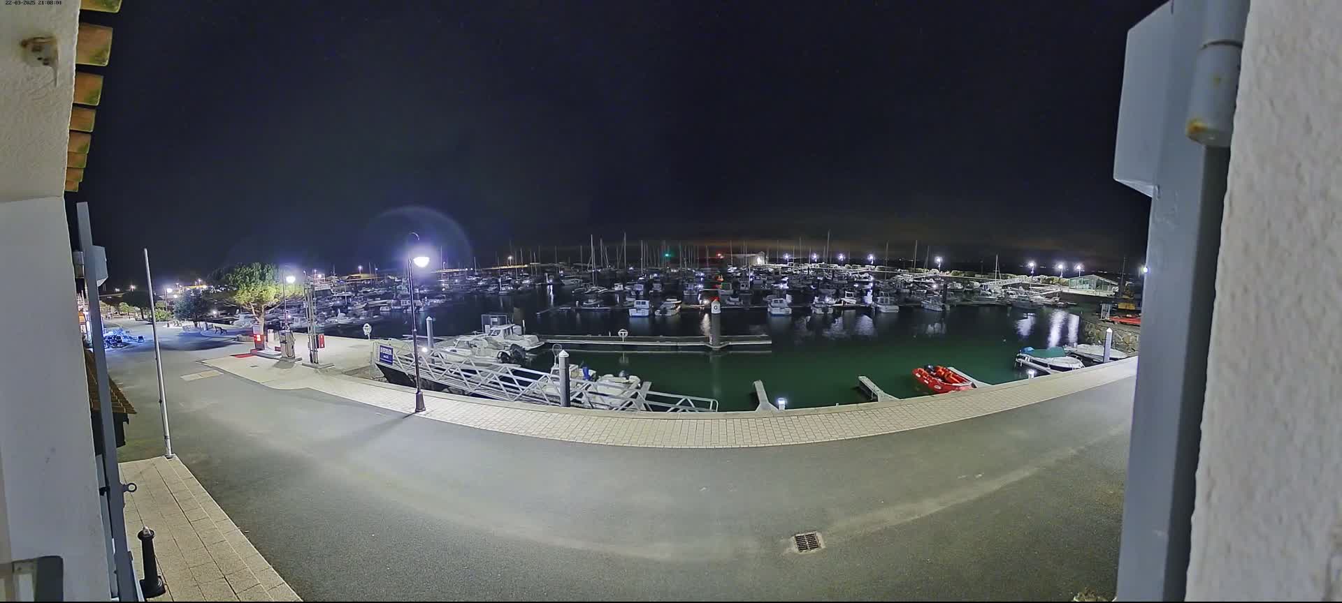 A nighttime view from a building shows a marina filled with numerous boats under a dark sky.