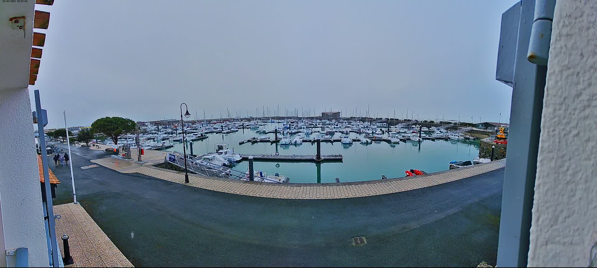 A marina filled with numerous boats is seen on an overcast day.